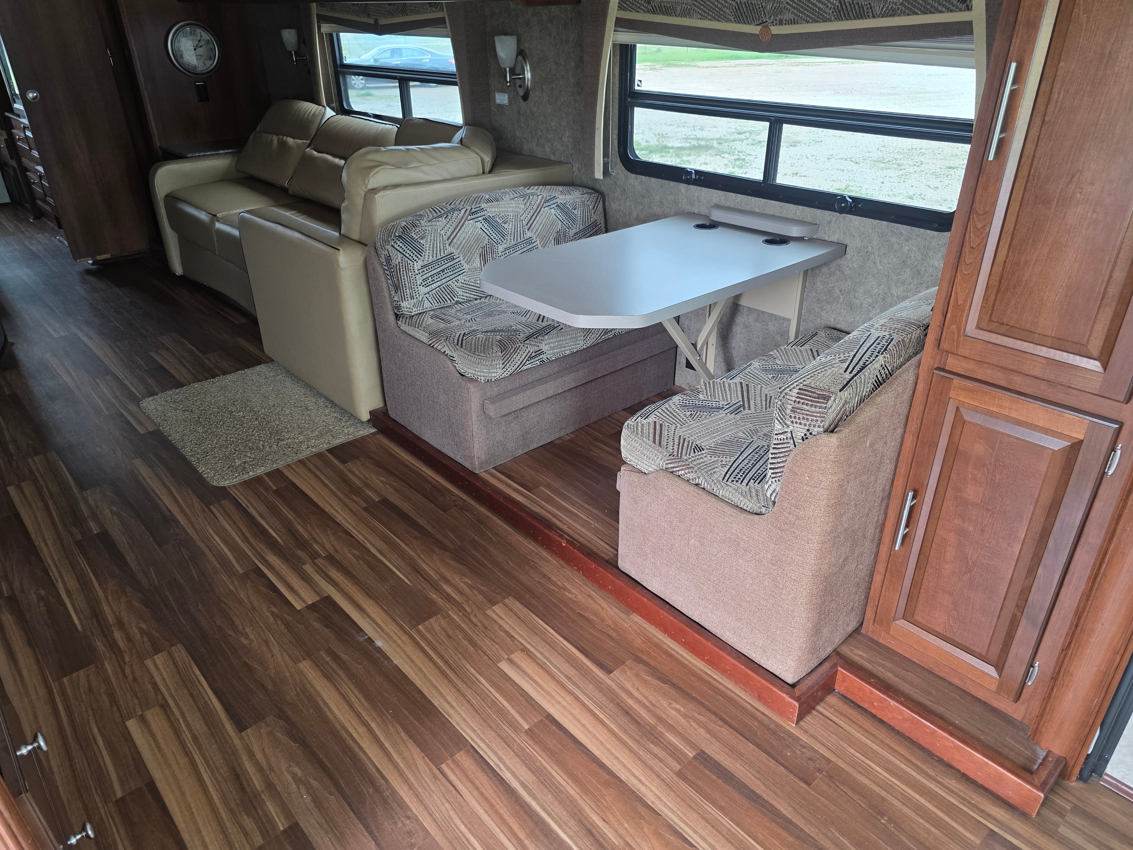 2014 Forest River Georgetown – living area with large sofa, dinette booth, swivel chair, wood flooring and panoramic windows