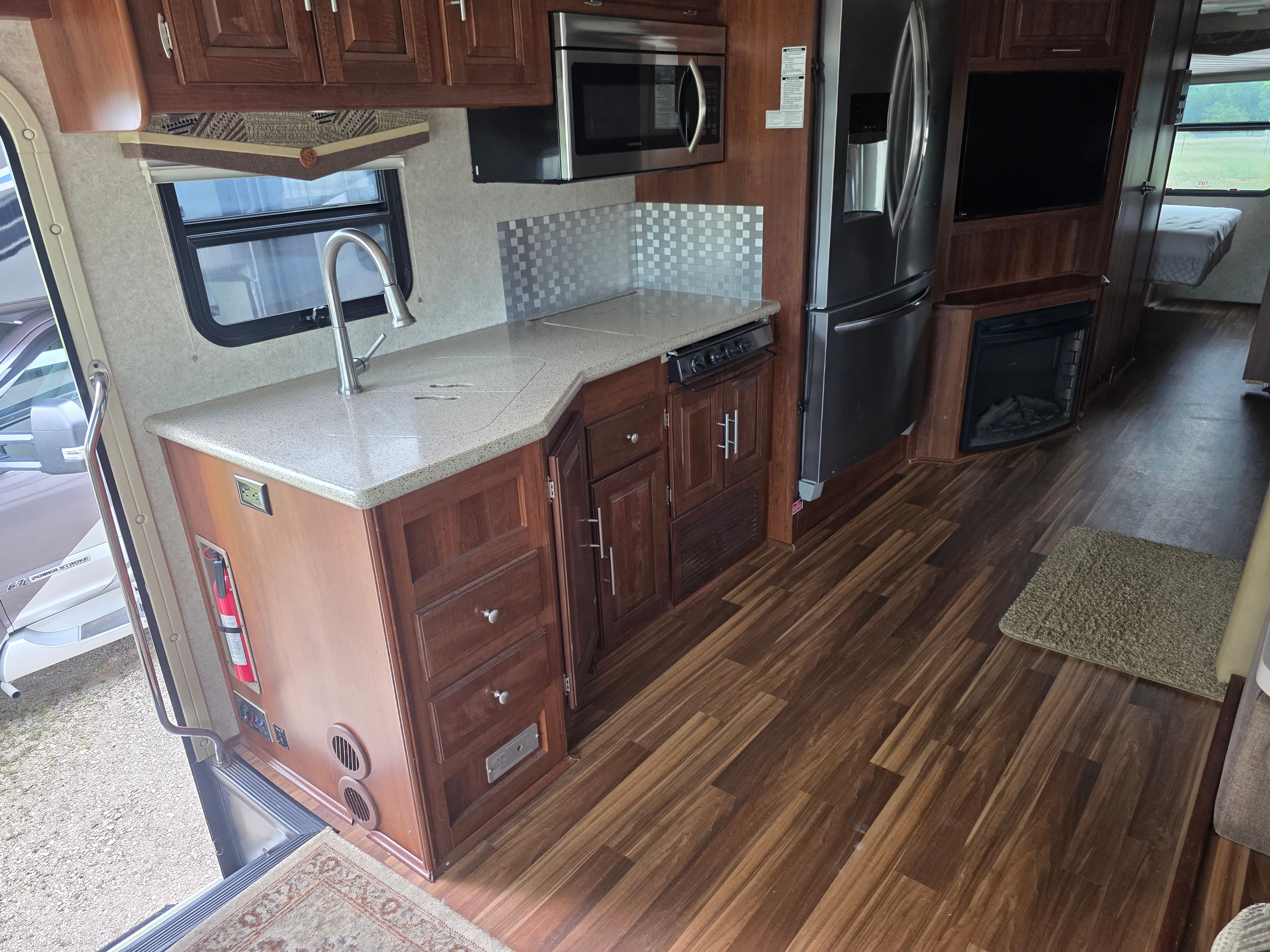2014 Forest River Georgetown – kitchen with granite countertop, stainless sink, cooktop, convection microwave, residential fridge and electric fireplace