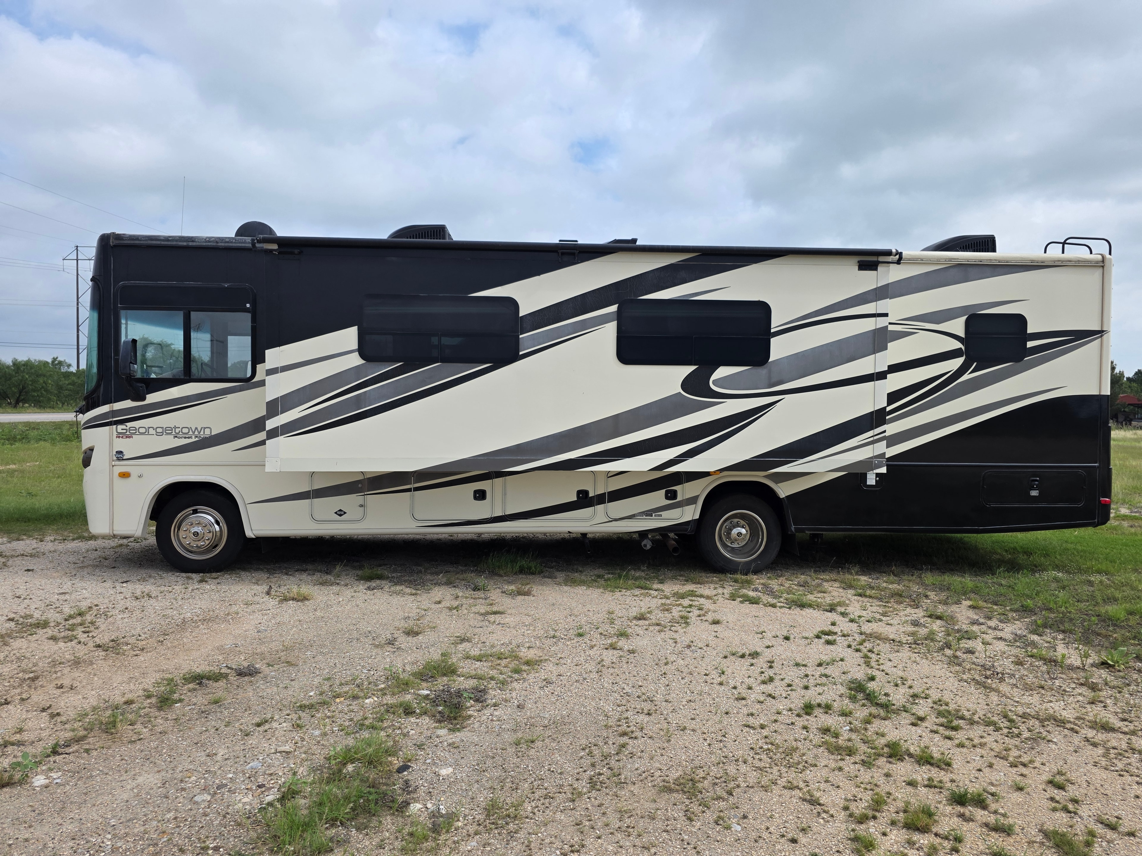 2014 Forest River Georgetown – full driver side with cream and black graphics and storage bays