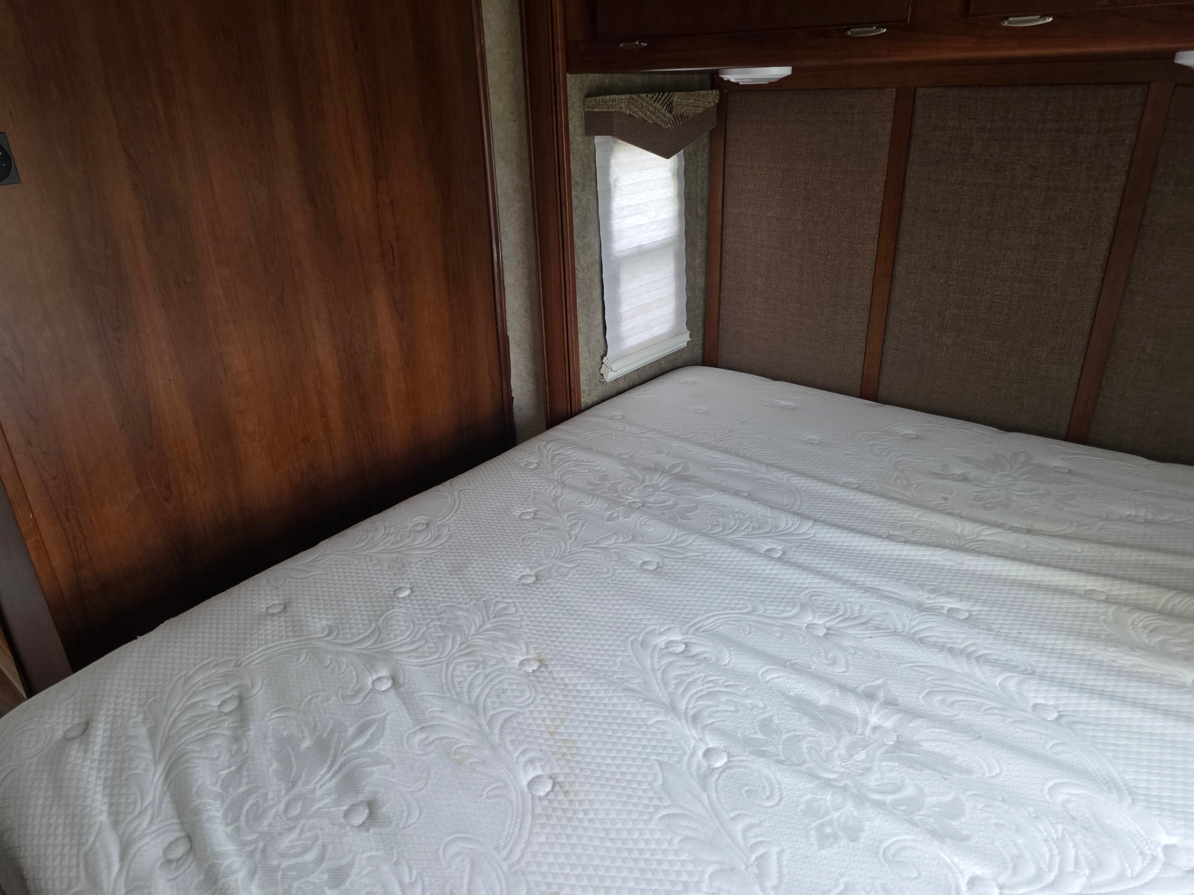 2014 Forest River Georgetown – bedroom headboard view with upholstered panels, wood cabinetry and window shade