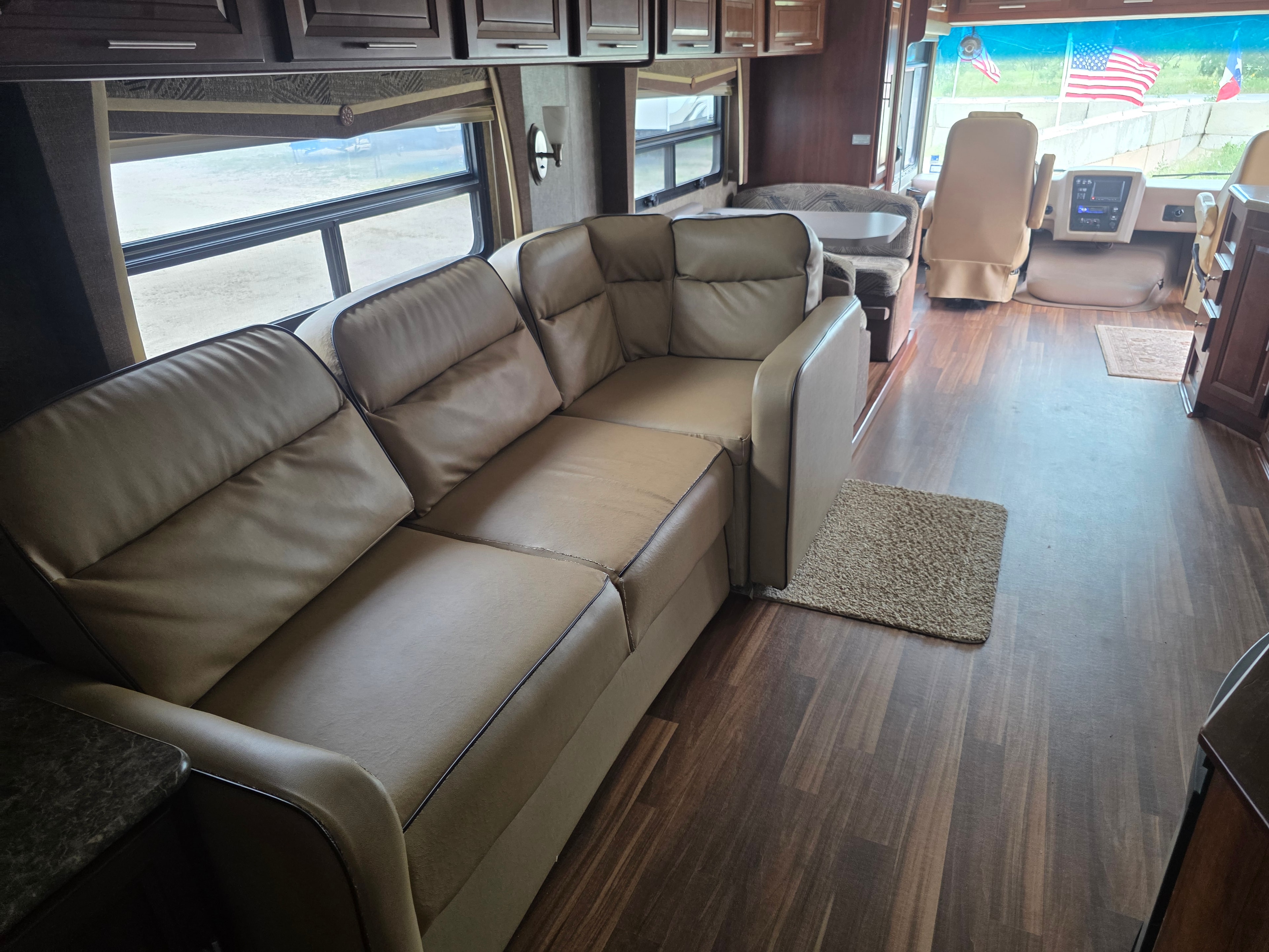2014 Forest River Georgetown – large L-shaped tan leather sofa with super slide open, wood flooring and cockpit view