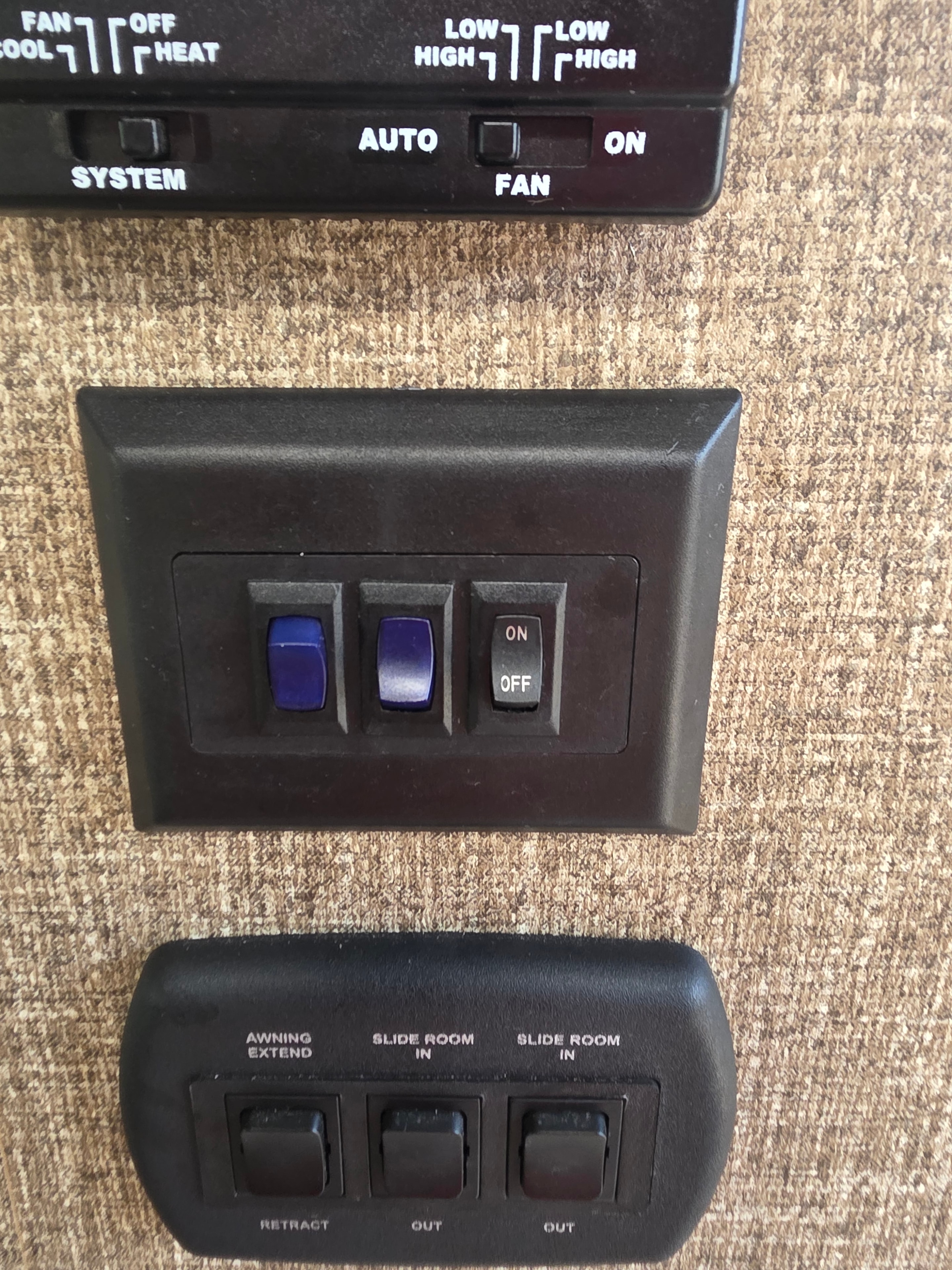 2014 Forest River Georgetown – interior wall panel with AC thermostat, on/off light switches, slide room in/out controls and awning extend/retract buttons