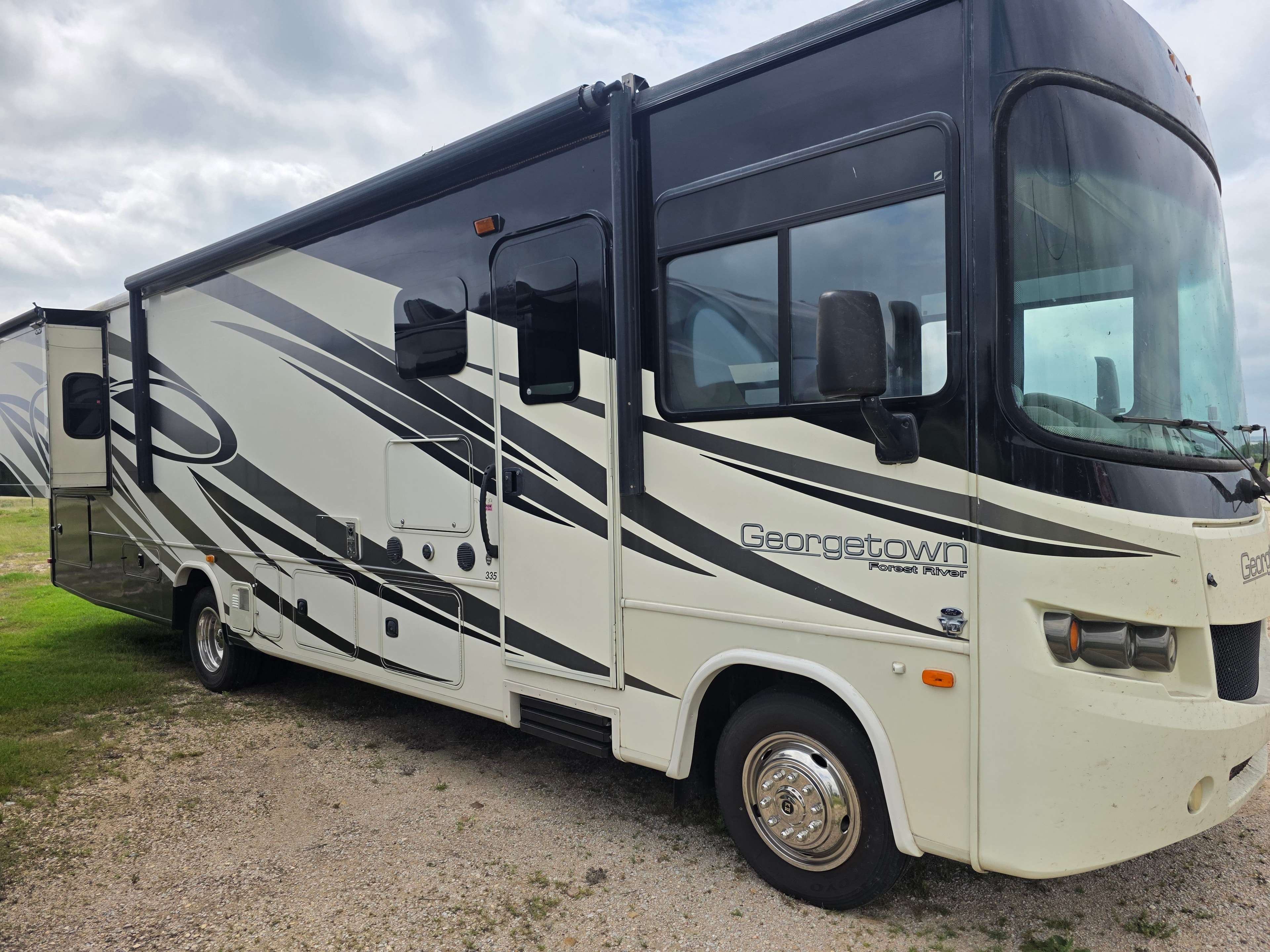 2014 Forest River Georgetown – passenger side with slide out, entry door, storage bays and Georgetown 335 badge