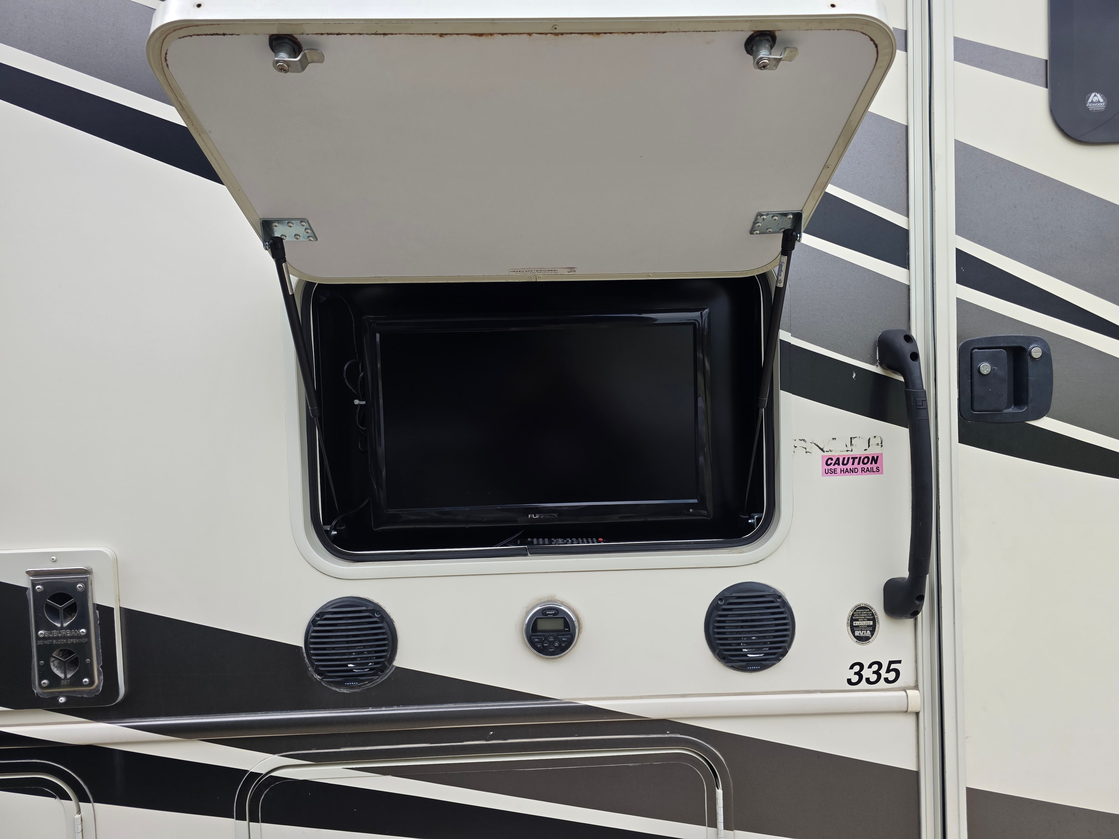 2014 Forest River Georgetown – exterior TV compartment open showing Furrion TV, speakers and stereo control