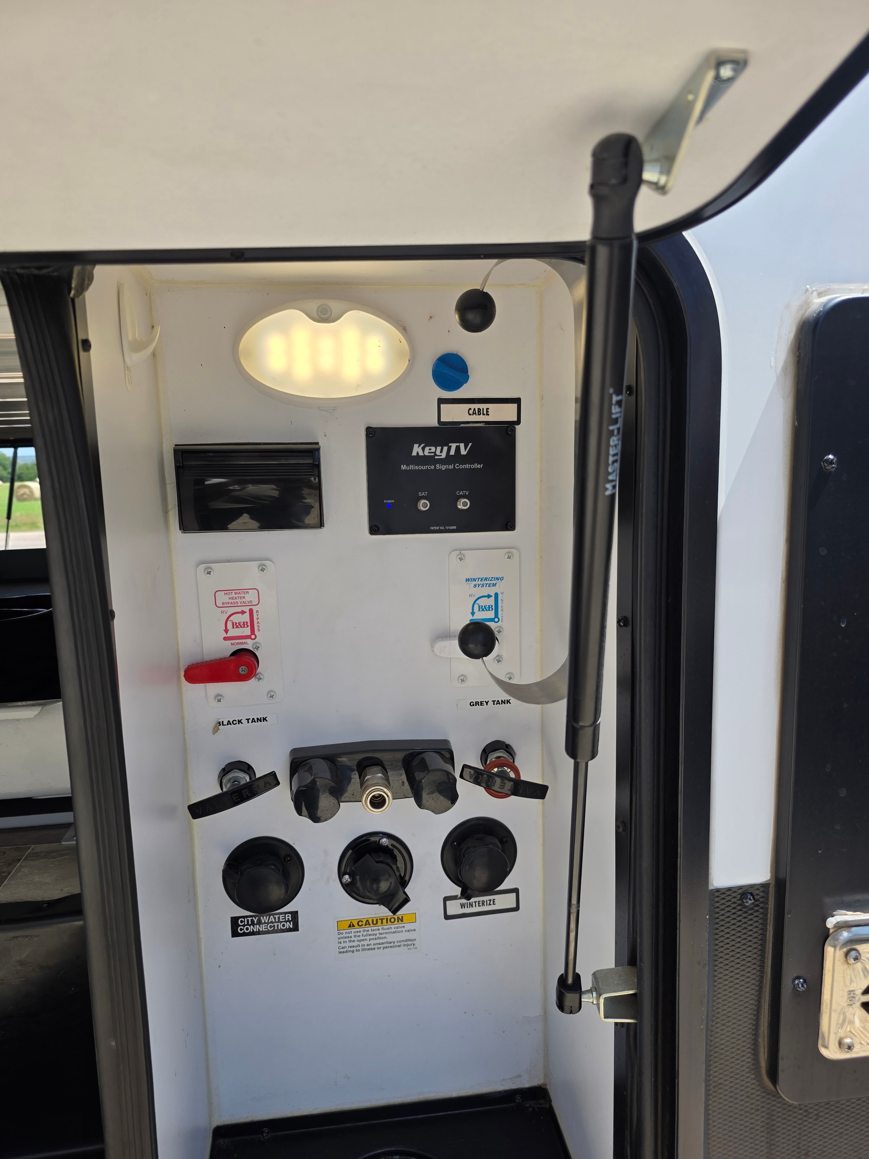 2021 Yukon Dutchmen 320RL – exterior utility panel with grey/black tank valves and city water