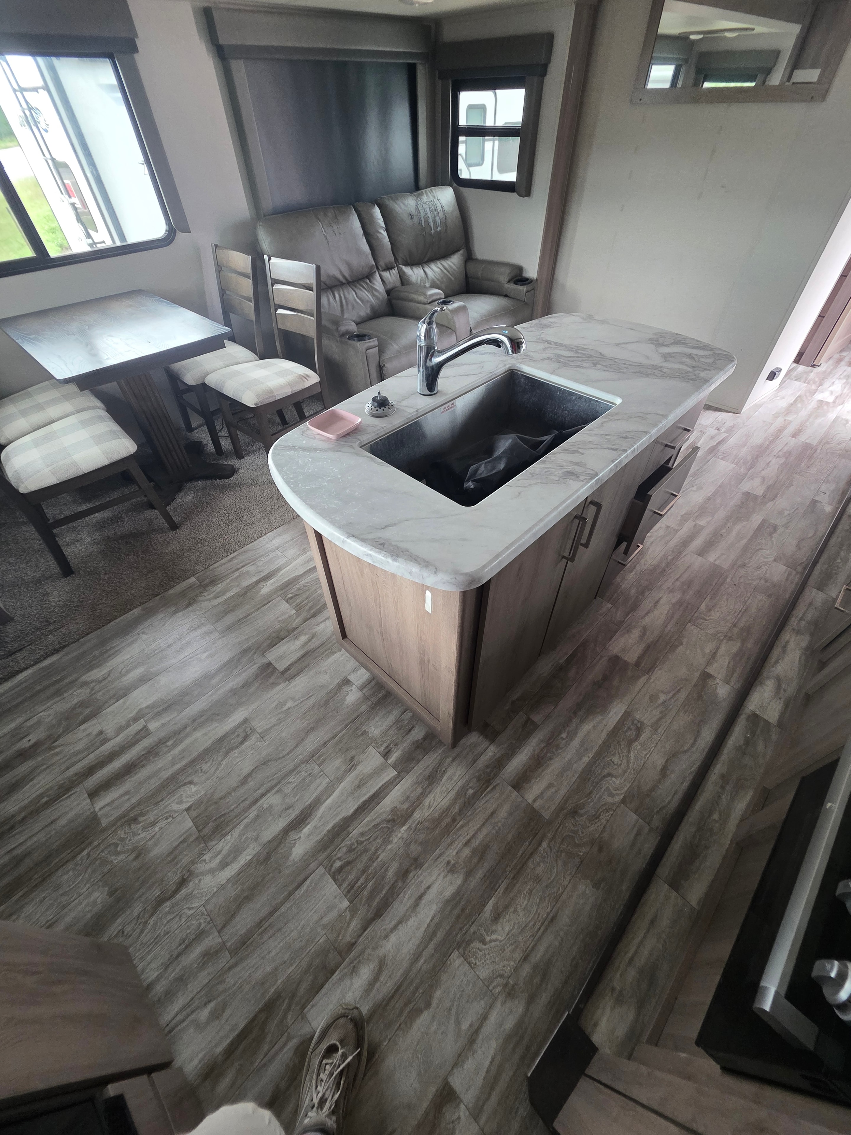 2022 Grand Design Imagine 2670MK – kitchen island with marble top and sink looking toward theater seating and dining area