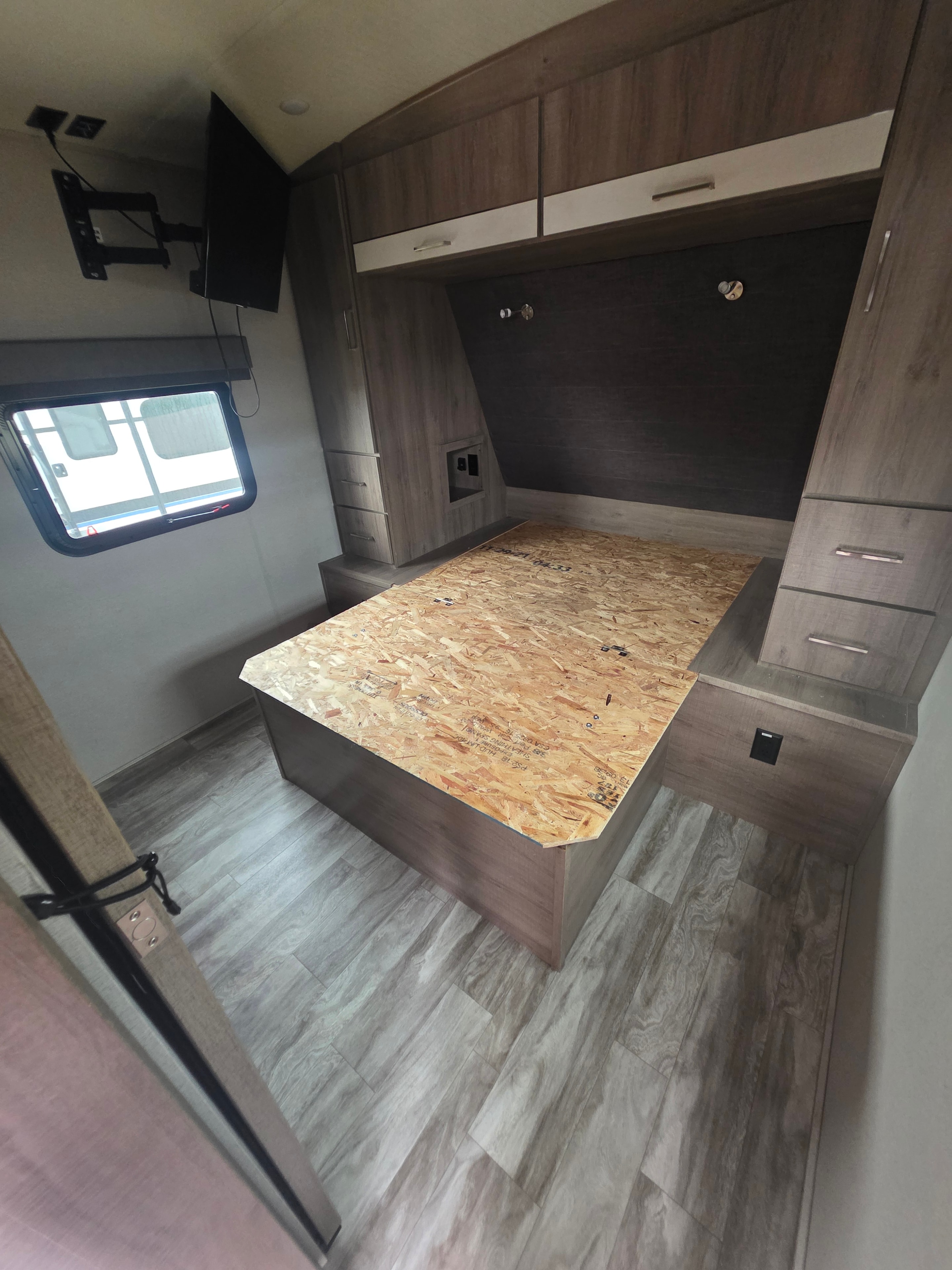2022 Grand Design Imagine 2670MK – bedroom with OSB TV lift platform, wardrobe, wall-mount TV arm and entry window