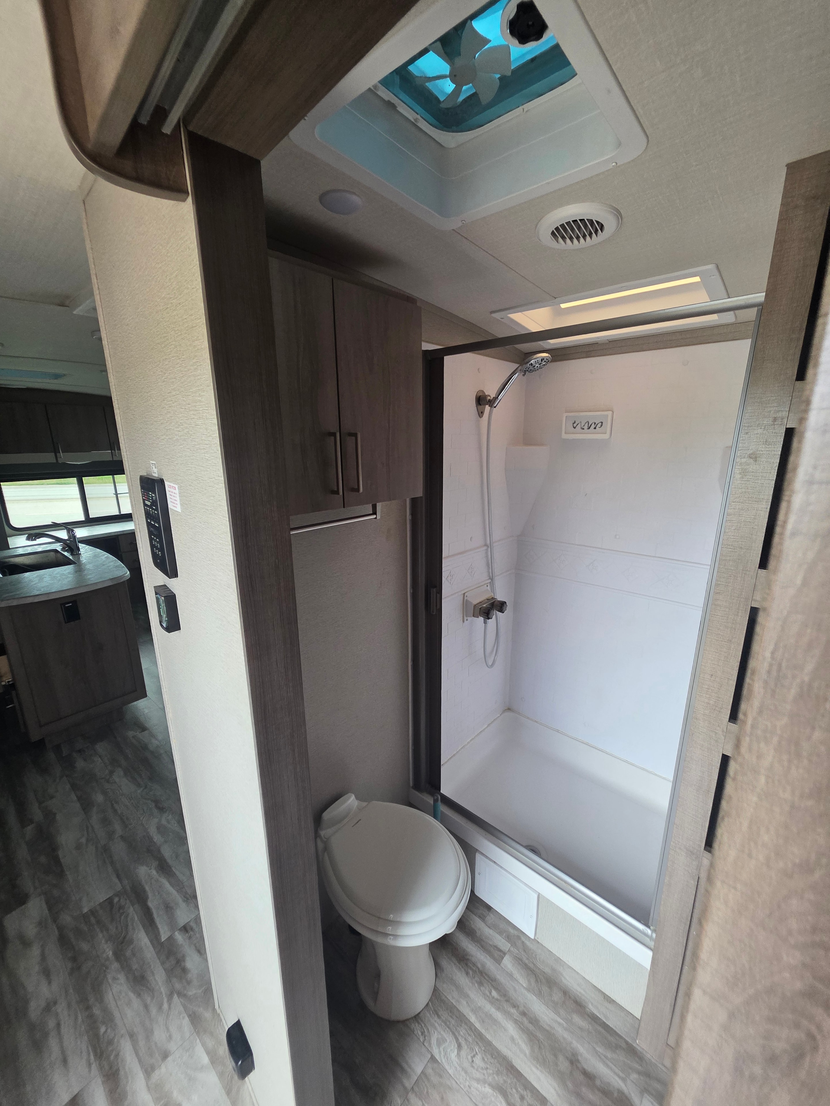 2022 Grand Design Imagine 2670MK – bathroom overview with large shower, toilet, vent fan and Compass Connect control panel