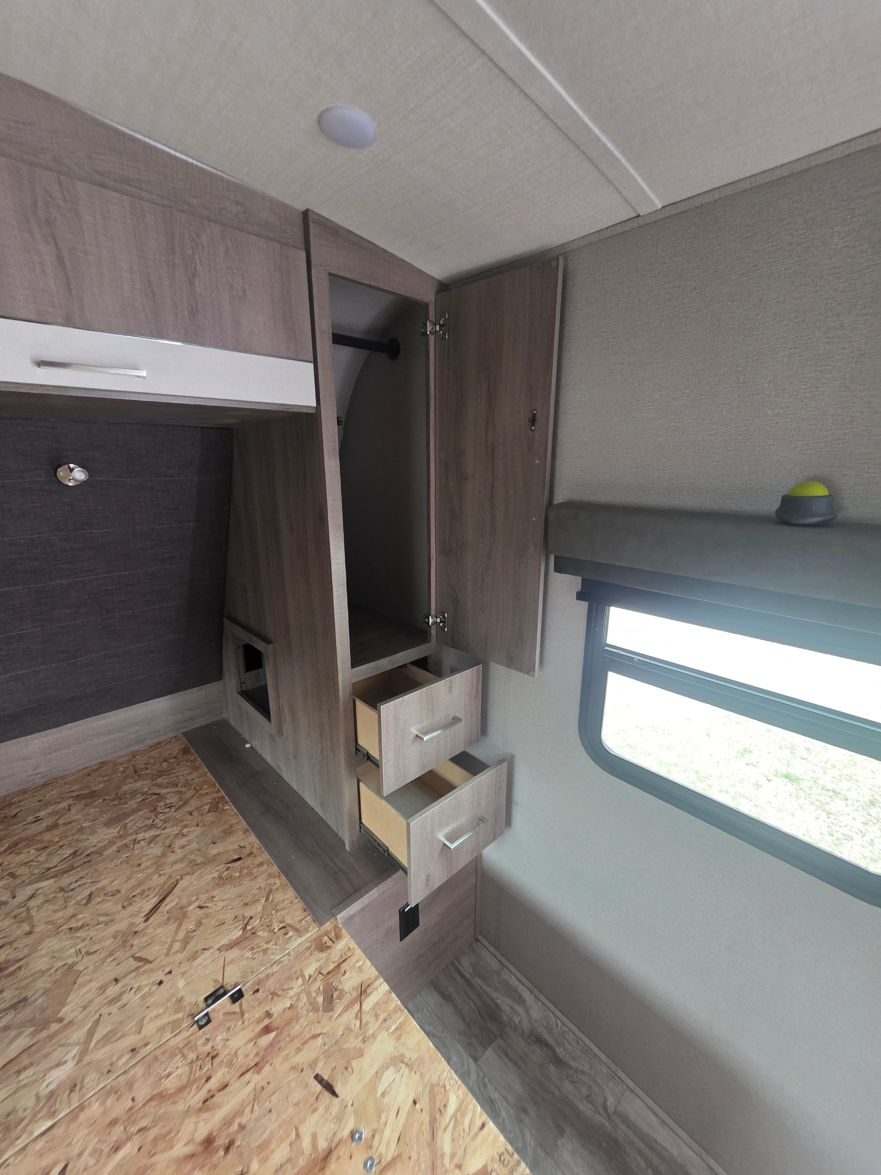 2022 Grand Design Imagine 2670MK – bedroom under-bed storage compartment open with drawers and OSB wall