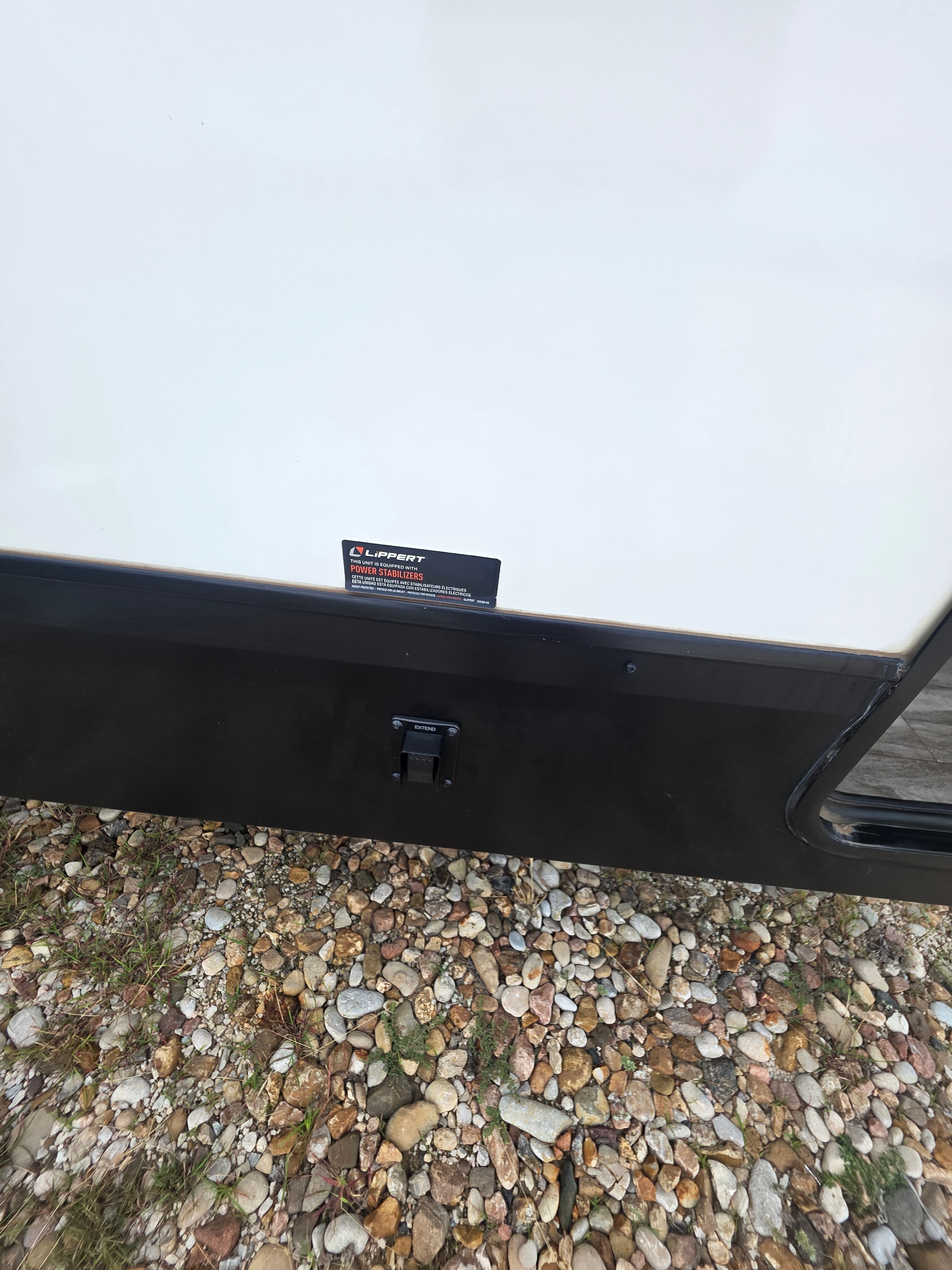 2022 Grand Design Imagine 2670MK – Lippert power stabilizer jack and warning label on exterior underbelly